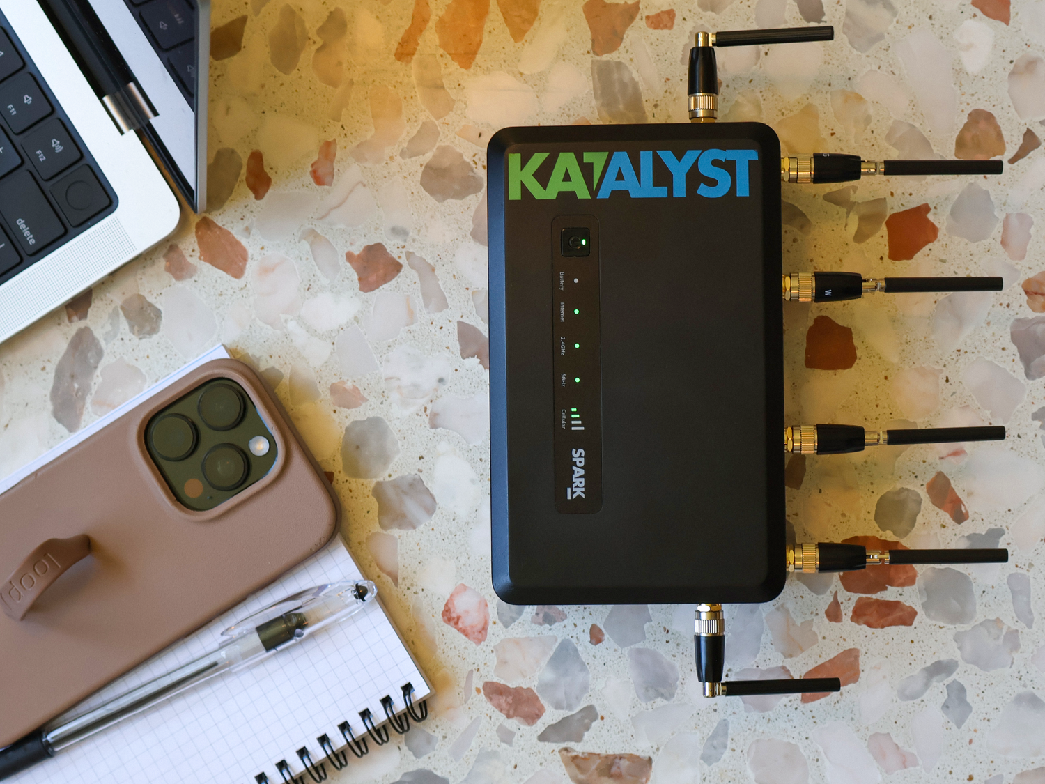 Katalyst Spark 5G cellular router on a desk with a phone and notebook.