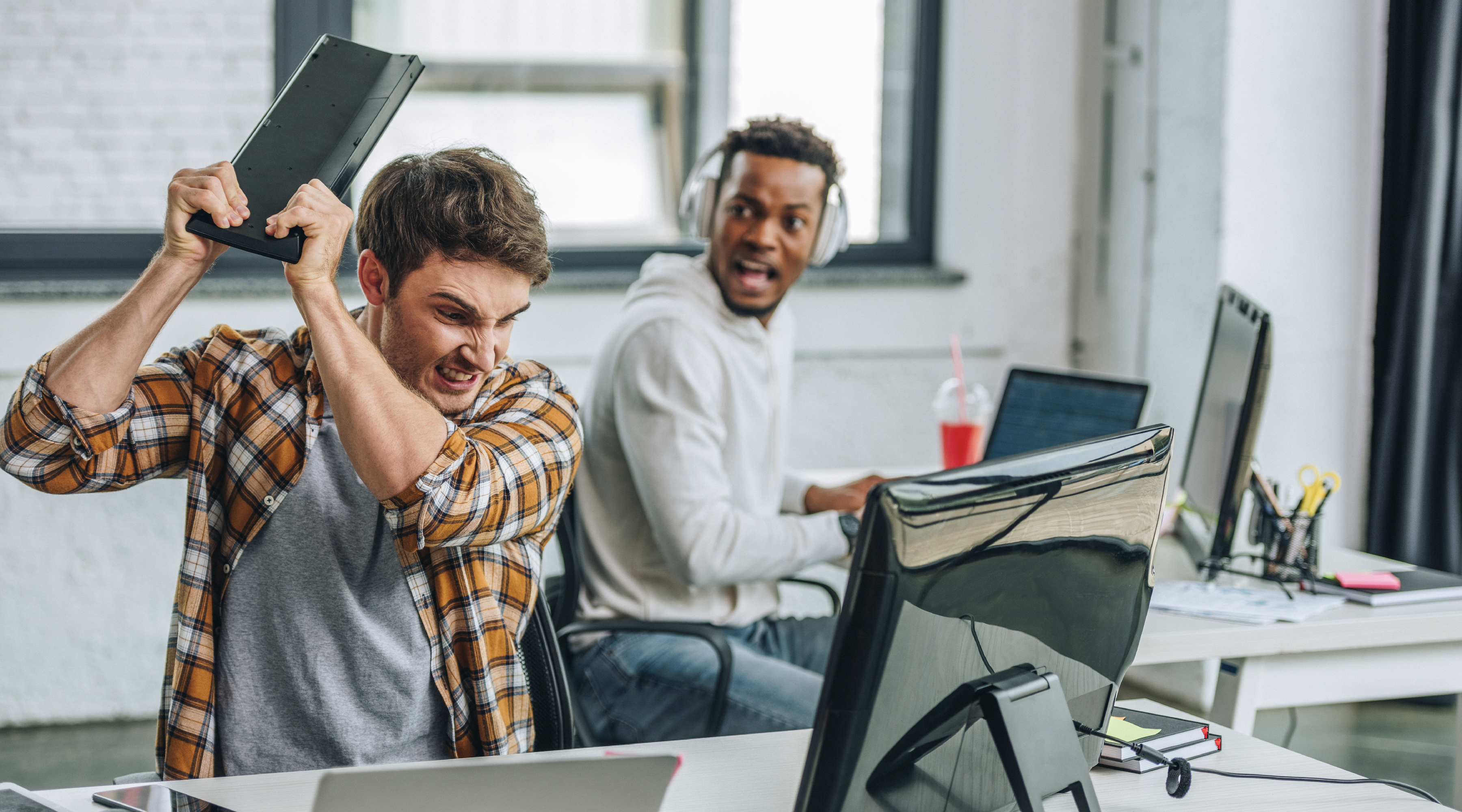 Office worker frustrated by unreliable internet while a coworker looks on.