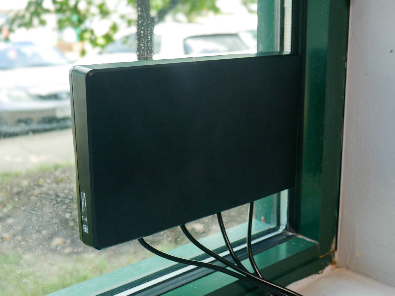 Katalyst Beacon indoor cellular antenna mounted to a window using a high-strength adhesive for quick, tool-free installation.