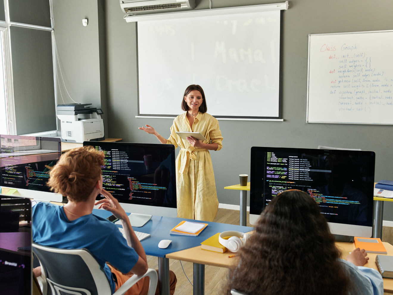 Instructor teaching a classroom of students using desktop computers.