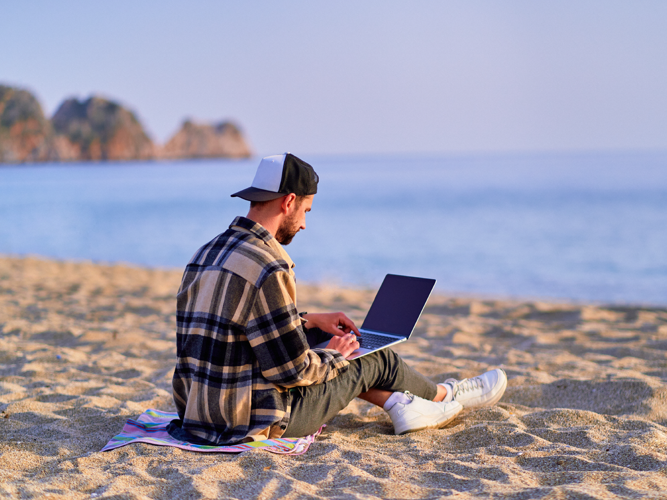 remote worker working on a laptop from a beach.