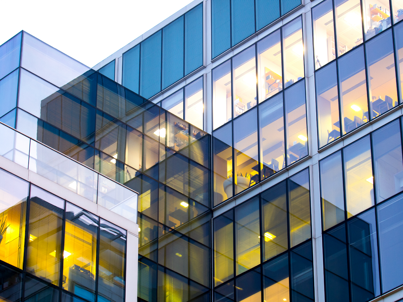 Modern office building with large glass windows representing improved indoor cellular coverage for business connectivity.