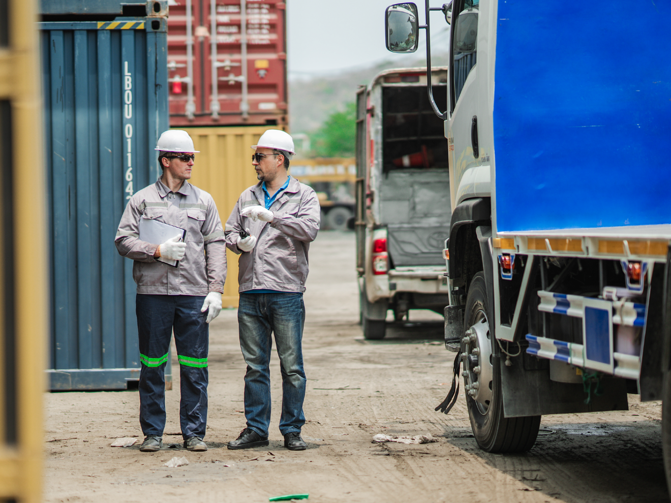 Fleet workers beside commercial trucks using connected networking equipment in the field.